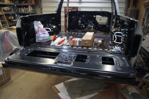 1979 Ford Bronco - The open tailgate and bed of a 1979 Ford Bronco are visible, filled with various parts and supplies.