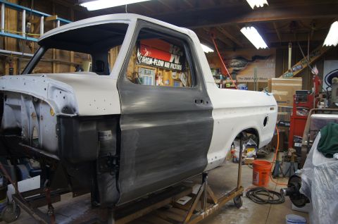 1979 Ford Bronco - Ford Bronco body in a workshop, showing primer and bare metal during restoration.