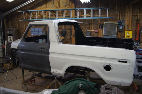 1979 Ford Bronco - This Ford Bronco body is undergoing restoration in a workshop, with parts of it in primer and others in white paint.