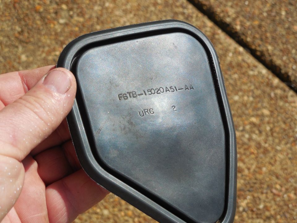 Hand holding a plastic engine part stamped F6TB-15020A51-AA