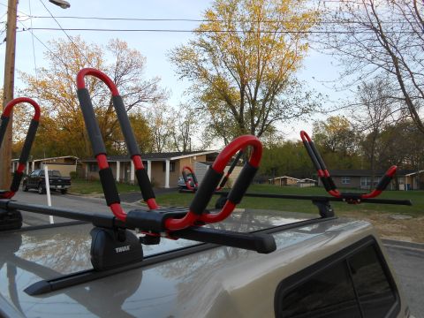 2000 Ford Ranger - A Thule kayak rack is mounted on the roof of a vehicle, with a black pickup truck visible in the background.