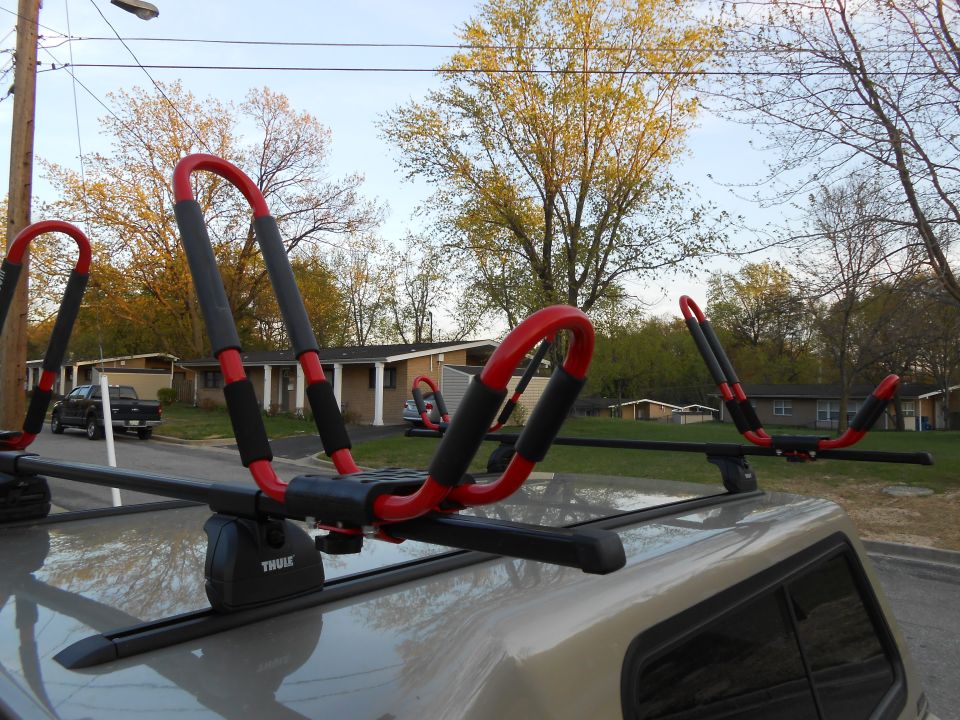Kayak rack on car roof with a black pickup truck in the background