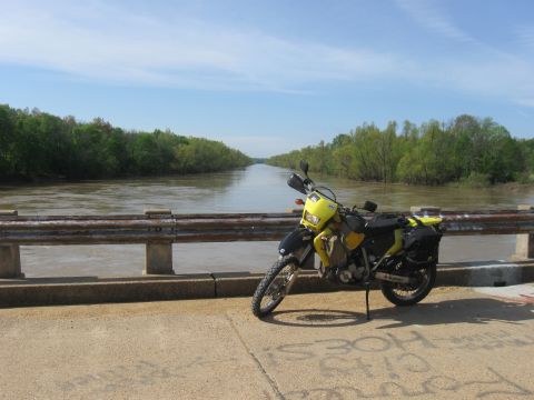 2006 Suzuki DR-Z400S - A yellow and black 2006 Suzuki DR-Z400S motorcycle is parked on a bridge, with a wide river and trees in the background.