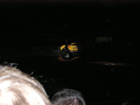 1996 Ford Bronco - A monster truck is illuminated on a dark stage, with spectators in the foreground.