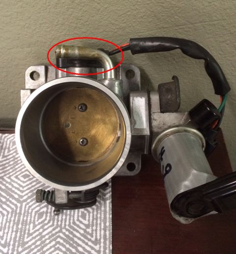 1993 Ford Bronco - Close-up of a Ford throttle body, showing a metal vacuum line connection.
