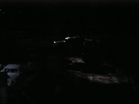 1996 Ford Bronco - A truck with oversized tires is visible at night, alongside a white car.