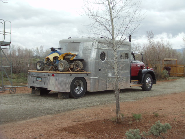 Custom truck with a camper shell and an ATV on the flatbed
