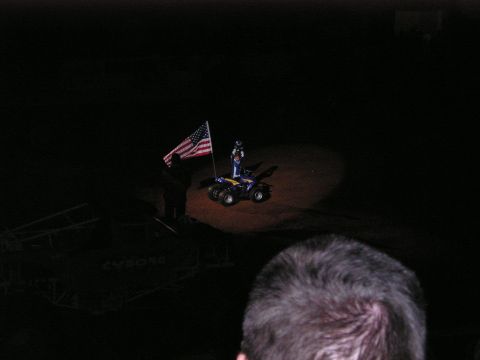 1996 Ford Bronco - A person stands on an ATV holding an American flag, illuminated by a spotlight in a dark arena.