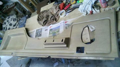 1982 Ford Bronco - A tan interior door panel is shown laid out on a workbench with tools and newspapers nearby.