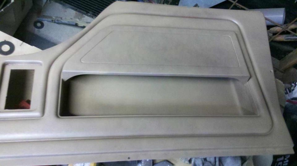 Tan interior door panel with a rectangular cutout and a large storage pocket
