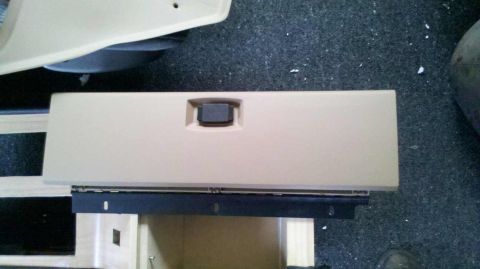 1982 Ford Bronco - Close-up of a tan glove box door, likely from an older vehicle's interior.