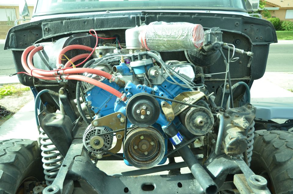 Truck engine bay with blue engine block, red hoses, and air filter