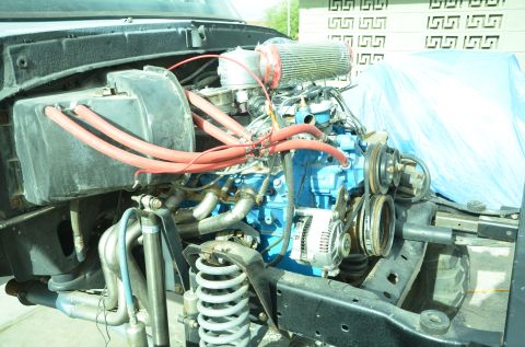 1979 Ford Bronco - Close-up of a vehicle's engine bay, showing a blue engine block and red hoses.