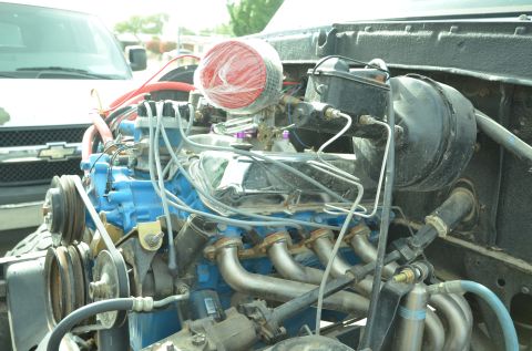 1979 Ford Bronco - Close-up view of an engine bay a blue engine block, chrome valve covers, and a red air filter, with another vehicle visible in the backgrou…