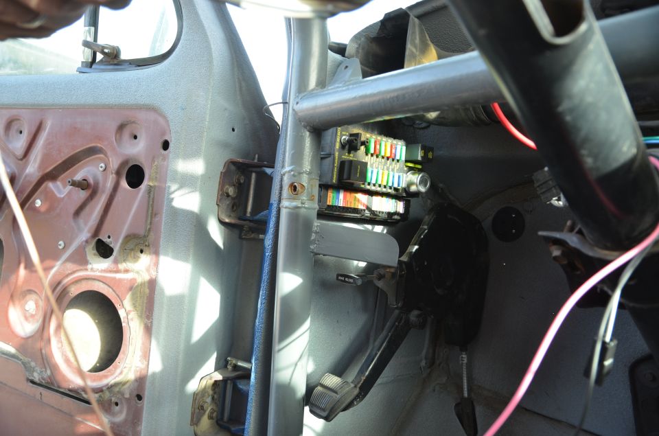 Interior shot of a vehicle's fuse box and wiring, with door panel removed
