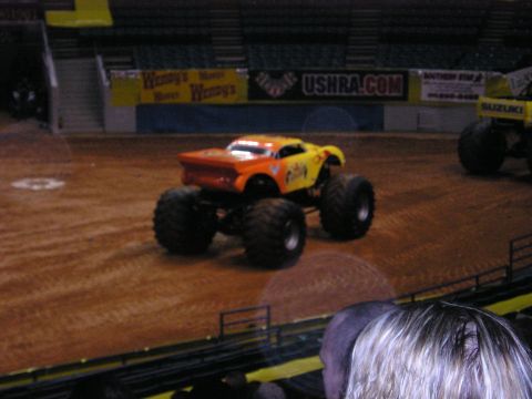 1996 Ford Bronco - Monster truck event in an arena with multiple trucks on display.