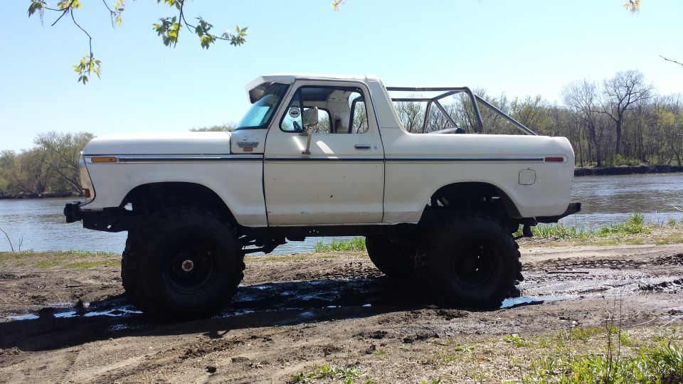 White lifted pickup truck with roll cage parked by a river