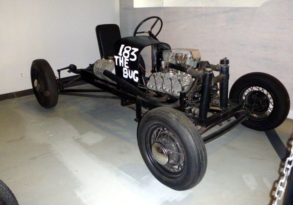 Custom hot rod with '183 THE BUG' painted on the side, exposed engine, and thin tires