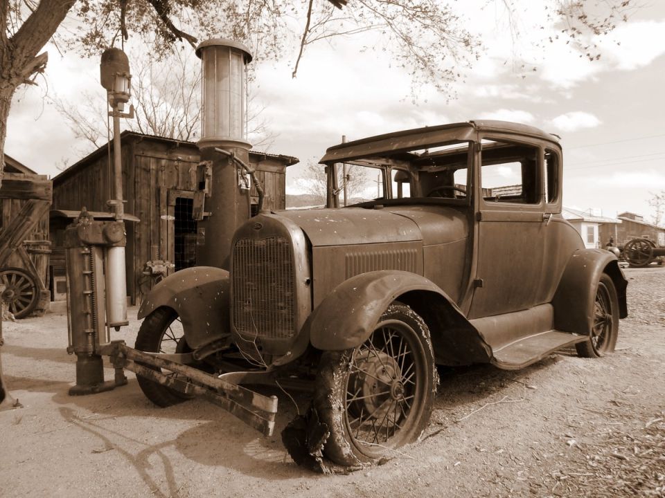 Brown 1928 coupe with flat tires at an old gas station