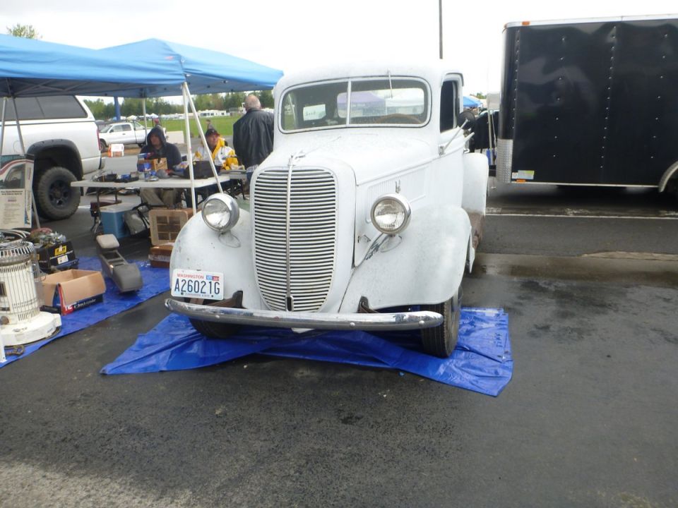White pickup truck with a chrome grille and bumper, parked on a blue tarp