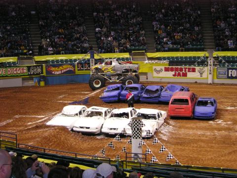1996 Ford Bronco - A monster truck event with several cars crushed on the dirt arena floor.