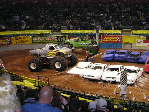 1996 Ford Bronco - Monster trucks perform in an arena, crushing cars as part of the show.