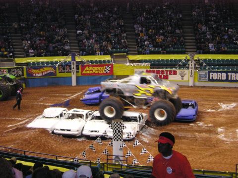 1996 Ford Bronco - Monster truck event with multiple cars crushed under a jumping monster truck.