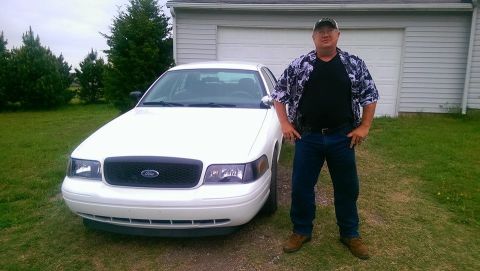 2000 Mercury Grand Marquis - Man poses with a white 2000 Mercury Grand Marquis parked in front of a garage.