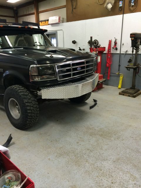 1993 Ford Bronco - Black Ford Bronco front with diamond plate bumper and aftermarket hood scoop in a garage.