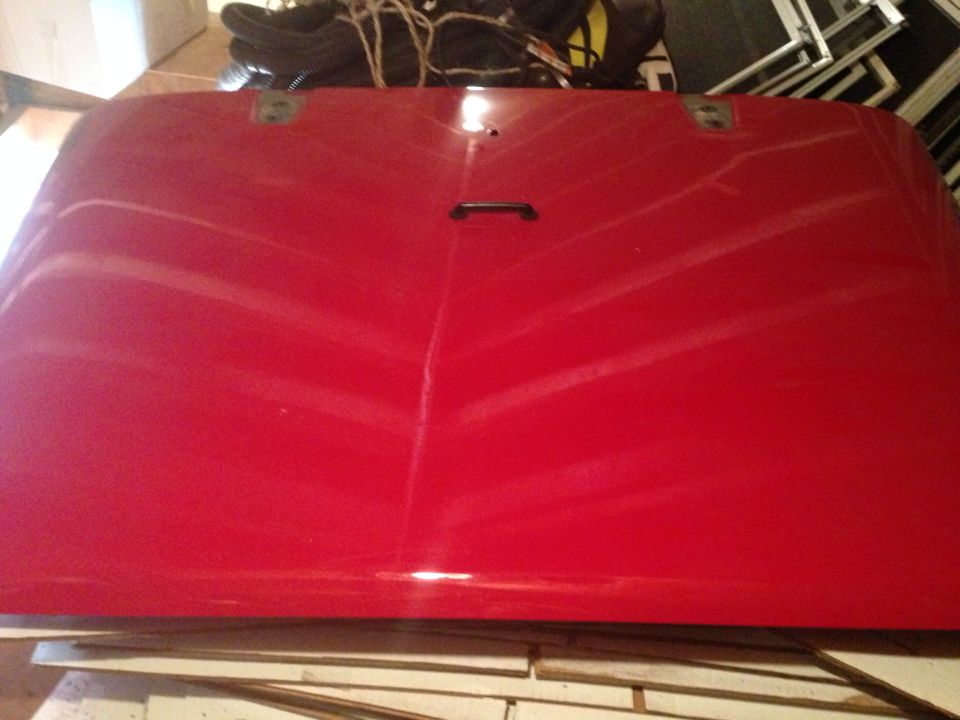 Red vehicle hood with a black handle and two mounting points