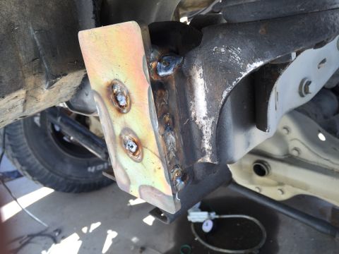 1995 Ford Bronco - Close-up view of a welded bracket on a vehicle's undercarriage, showing mechanical components.