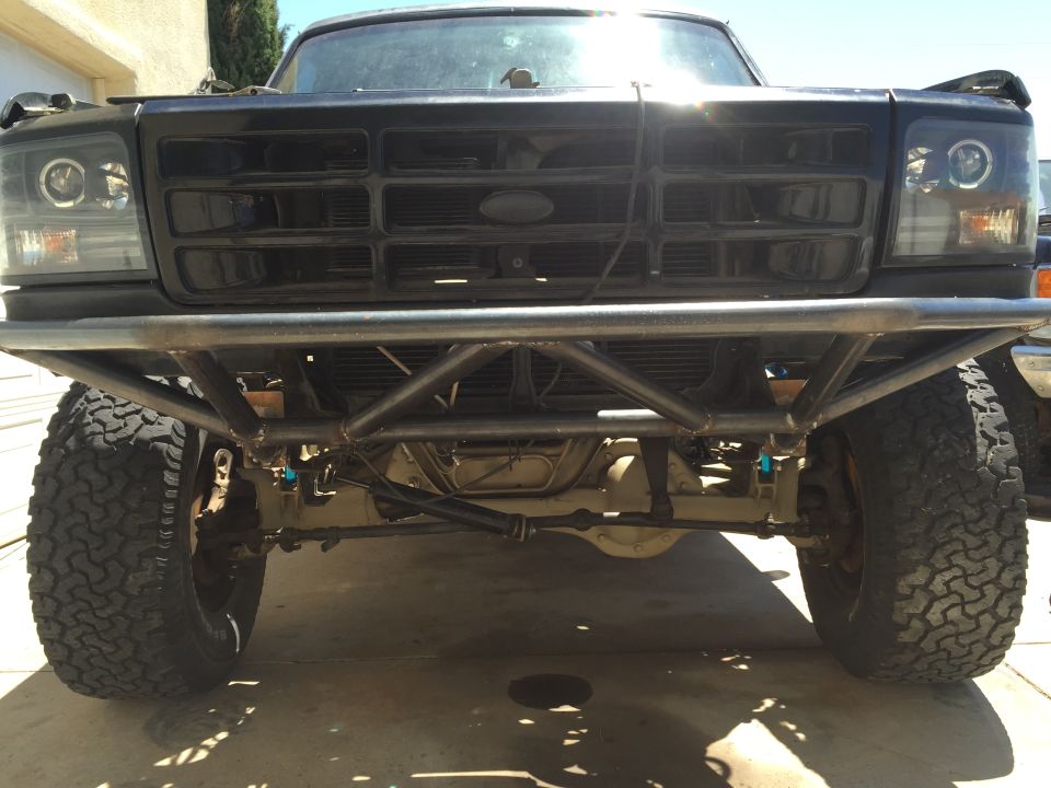 Front view of a black Ford truck with a large aftermarket bumper and off-road tires