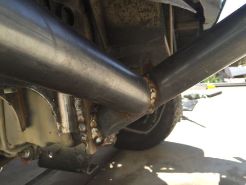 1995 Ford Bronco - Custom exhaust pipe welded to vehicle frame, with a tire visible in the background.