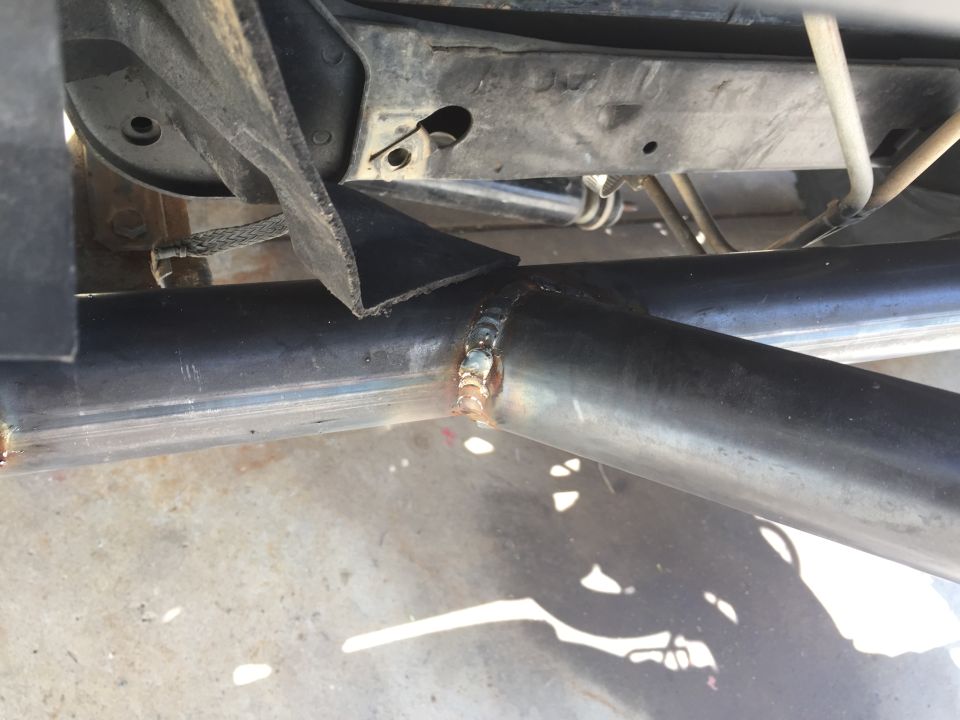 Welded metal frame components with visible weld beads and a black rubber flap