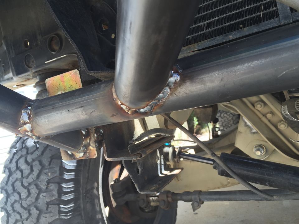 Close-up of welded tubing, part of a custom roll cage, with suspension components and tire visible