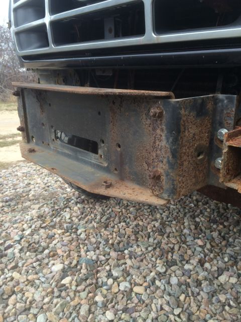 1993 Ford Bronco - A heavily rusted bumper bracket is attached to the front of a vehicle.