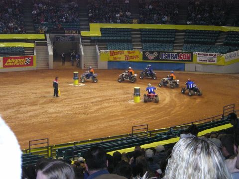 1996 Ford Bronco - ATVs compete in a race event held inside an arena, with banners and spectators visible.