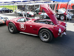 1900 Ford Mustang II - Red AC Cobra replica with number 88 on the door, engine exposed under the open hood.