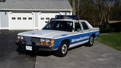 1991 Ford LTD Crown Victoria - A 1991 Ford Crown Victoria LTD police car is parked in front of a residential garage.