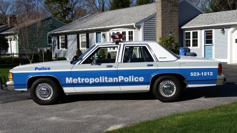 1991 Ford LTD Crown Victoria - Side view of a 1991 Ford Crown Victoria LTD police car parked in front of a suburban house.