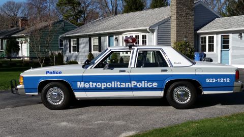 1991 Ford LTD Crown Victoria - This police car, marked 'Metropolitan Police', is parked in front of a suburban house.