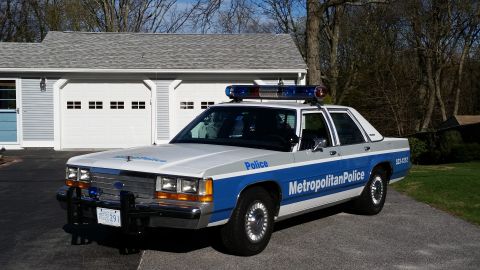 1991 Ford LTD Crown Victoria - Metropolitan Police car, a 1991 Ford Crown Victoria LTD, parked in front of a garage.