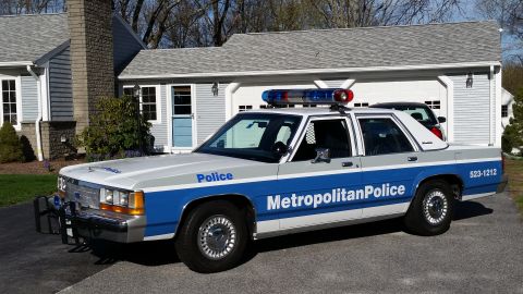 1991 Ford LTD Crown Victoria - A 1991 Ford Crown Victoria LTD police car is parked in front of a suburban garage.