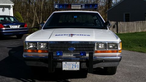 1991 Ford LTD Crown Victoria - A 1991 Ford Crown Victoria LTD police car is parked in front of a house, with another police car visible in the background.