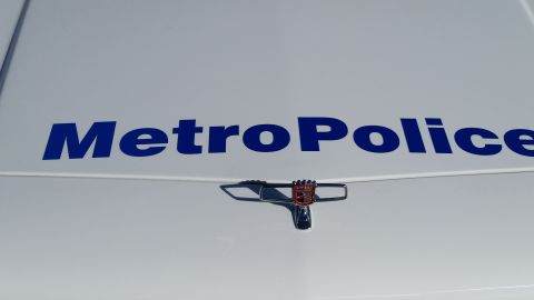 1991 Ford LTD Crown Victoria - Close-up of a white vehicle's hood displaying "Metro Police" text and a distinctive chrome emblem.