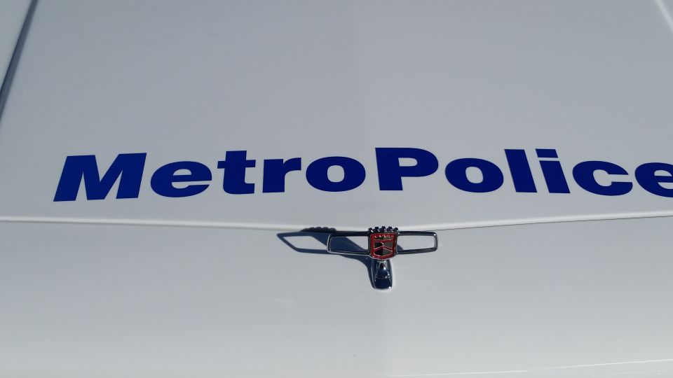 White car hood with blue "Metro Police" text and a chrome emblem with a red shield
