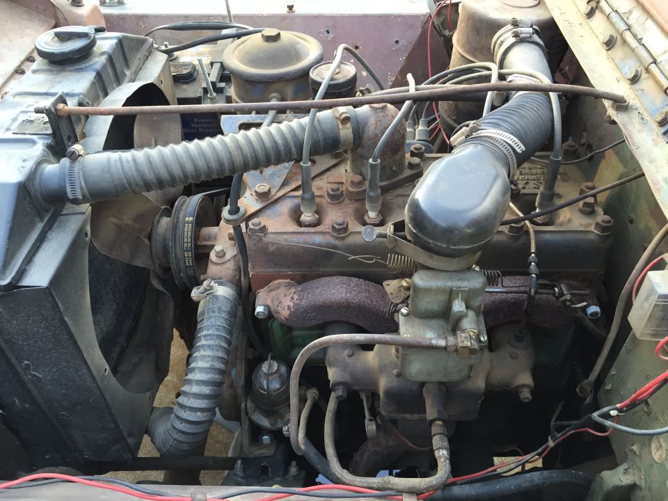 Engine bay with a rusty inline-four engine, radiator, and hoses