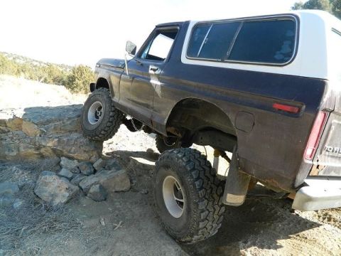 1979 Ford Bronco - SUV navigates a rocky trail with its front wheels on a ledge.