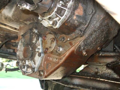 1979 Ford Bronco - Underside view of a heavily soiled vehicle transfer case, showing bolted components and fluid leaks.