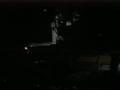 1996 Ford Bronco - A robot stands tall at a monster truck show, illuminated by spotlights.